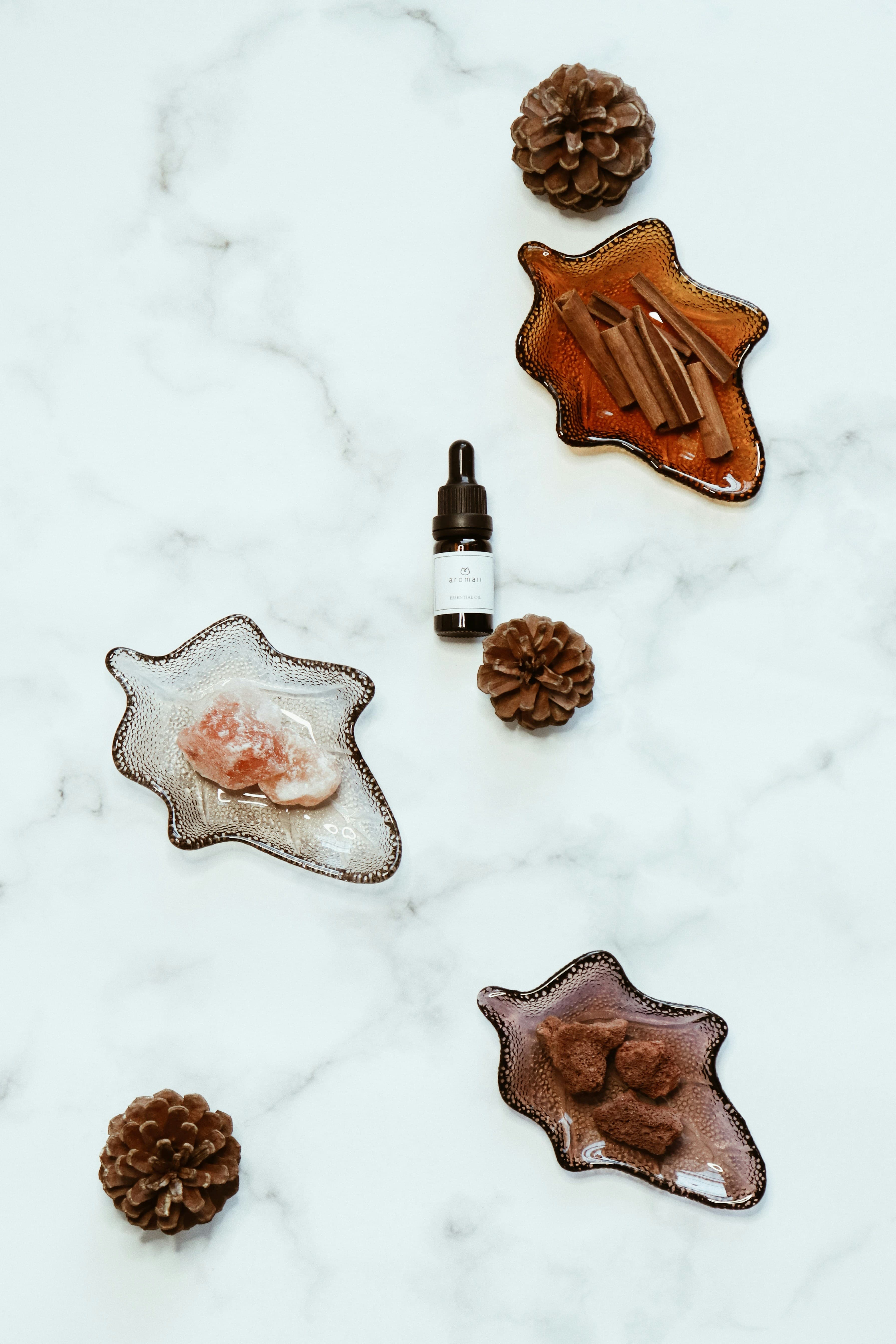 Array of natural perfume ingredients including dried flowers, essential oil bottles, and botanical extracts arranged on white marble surface